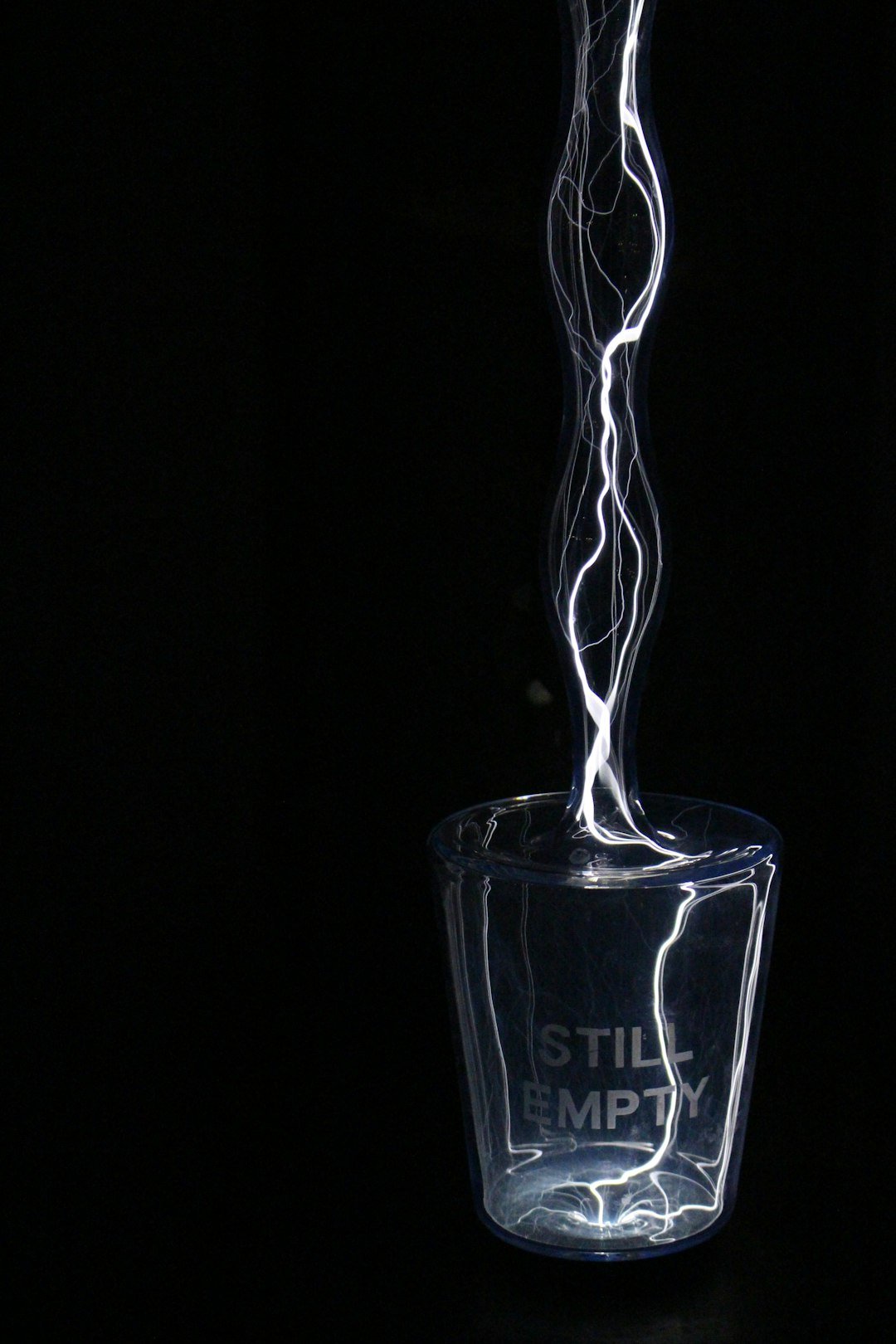 An empty glass is filled with electric charge, with lightnings. Still empty is written on the glass.
