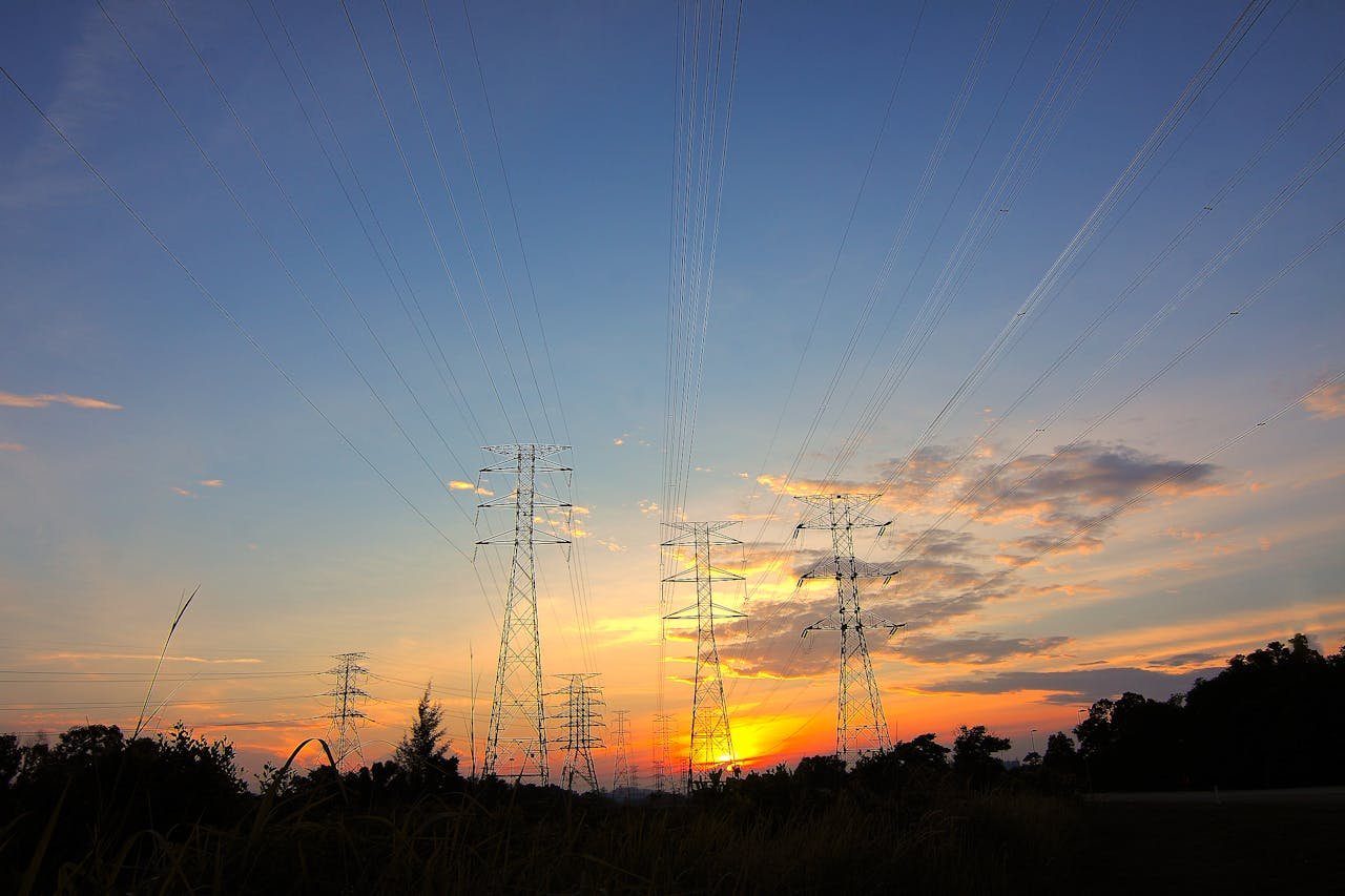 Silhouette of power lines against a dramatic sunset sky in a rural landscape.